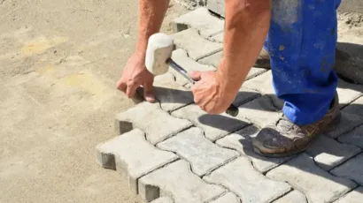 Worker aligning concrete interlock pavers with a rubber mallet